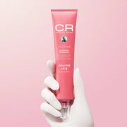Pink tube of Dr. Groot skincare product held by a gloved hand on a pink background