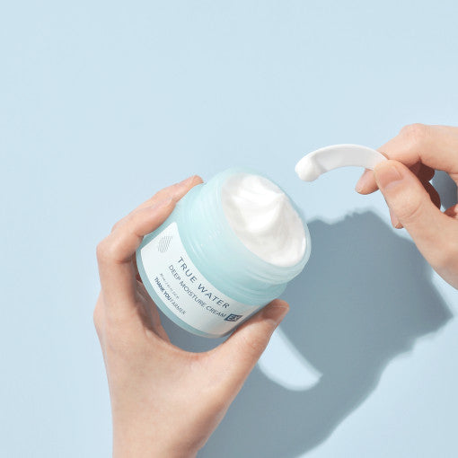 Person opening a jar of cream on a light blue background