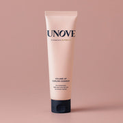 UNOVE Volume Up Curling Essence 147ml in soft beige tube with minimalist design, placed diagonally on a neutral backdrop