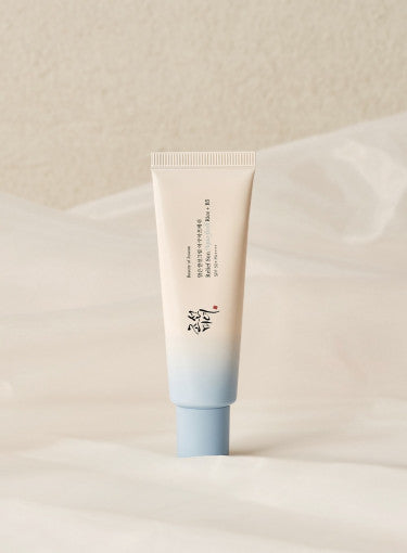 Beauty of Joseon Relief Sun Aqua-fresh Rice+B5 in a tube beside ice cubes with flowers, showcasing hydration and UV protection.